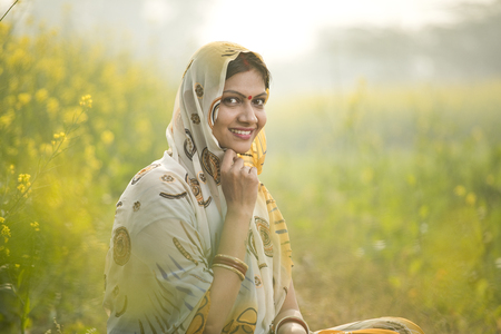 Smiling woman farmer in rapeseed agricultural fieldの写真素材