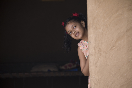 Little Indian girl peeking out of her houseの写真素材