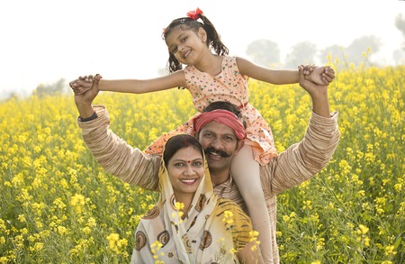 Portrait of happy rural family in rapeseed agricultural field