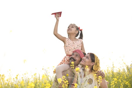Girl sitting on fathers shoulder and throwing paper airplaneの写真素材