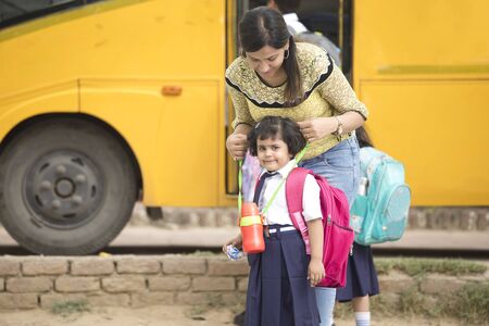 Teacher talking with student before they get on school busの写真素材