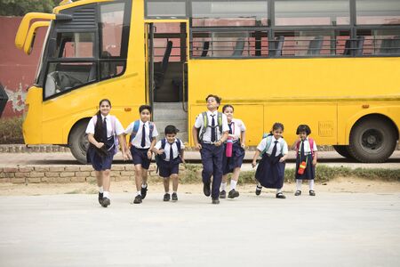 Schoolboys and schoolgirls walking of the school bus