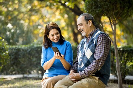 Senior woman sharing media content with her husband using mobile phoneの写真素材