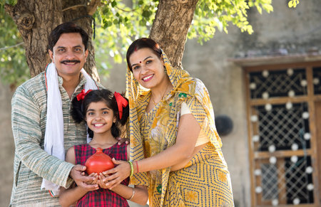 Rural Indian family with daughter holding piggy bankの写真素材