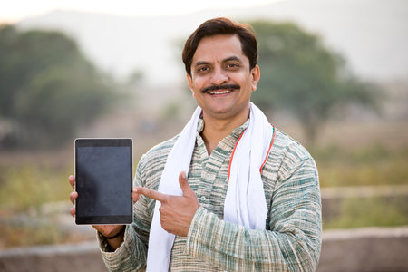 Happy rural Indian farmer showing digital tablet screenの写真素材
