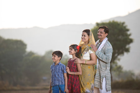 Happy rural Indian family looking away at agricultural fieldの写真素材