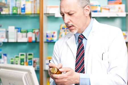 Pharmacist writing on a pill bottleの写真素材