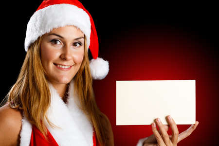 Portrait of a beautiful Christmas girl holding a blank cardの写真素材