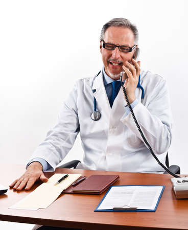 Senior doctor talking on the phone in his officeの写真素材