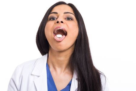 Doctor showing a medicine on her tongueの写真素材