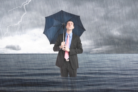 Businessman holding an umbrella in the seaの写真素材