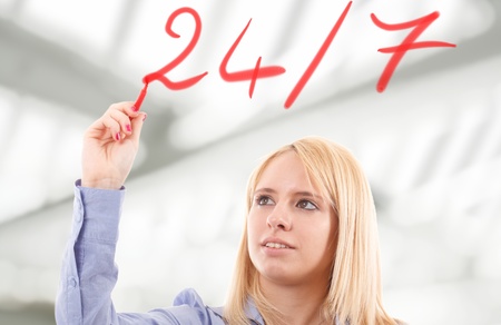 Beautiful blonde businesswoman writing 24 7