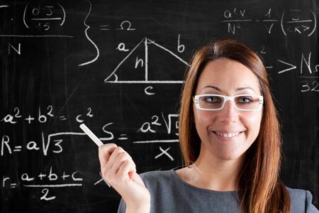 Friendly teacher showing formulas on a blackboard