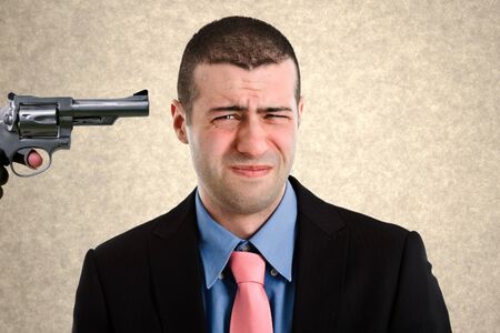 Businessman with a gun pointed to his headの写真素材