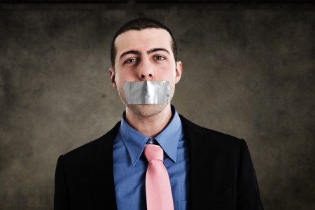Portrait of a businessman having the mouth closed with tapeの写真素材