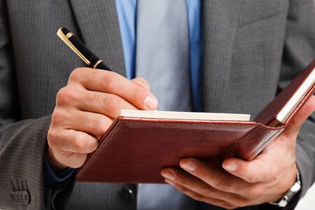 Detail of a businessman writing on his agendaの写真素材