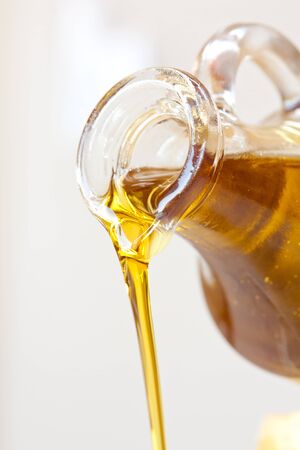 Extra virgin olive oil pouring from a bottleの写真素材