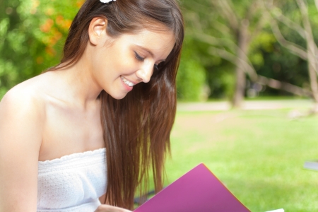 Portrait of a young beautiful woman reading a book in the parkの写真素材