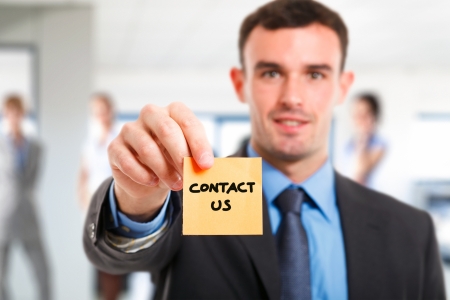 Businessman showing the words contact us on a post-itの写真素材