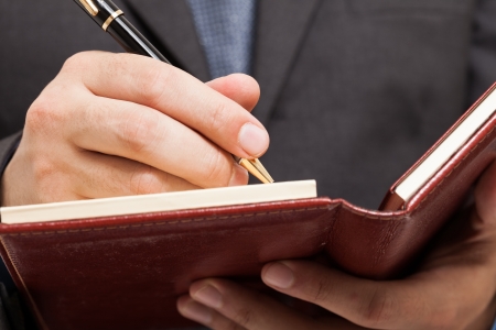 Detail of a businessman writing on his agendaの写真素材