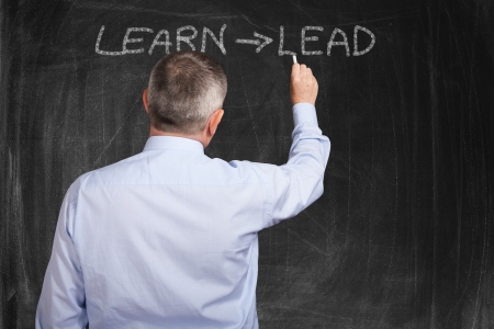 Smiling man writing a motivational concept on a blackboardの写真素材