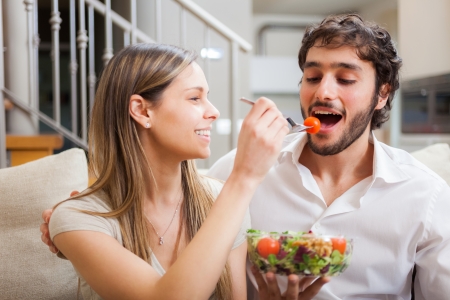 Couple eating a salad in the living roomの写真素材