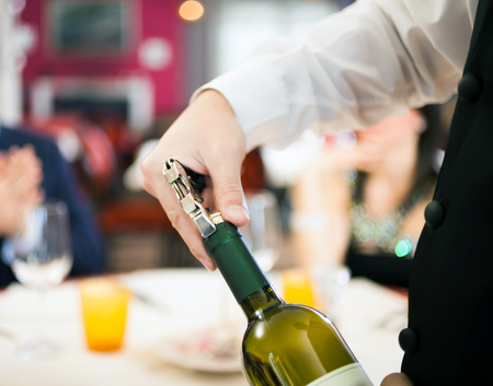Waiter uncorking a wine bottle in a restaurantの写真素材
