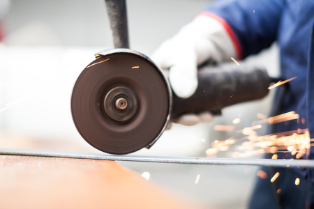 Worker using a grinder on a metal plate