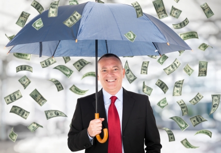 Happy man holding an umbrella in a money rainの写真素材