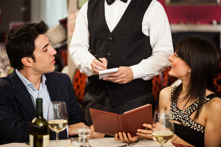 Couple ordering dinner in a restaurantの写真素材