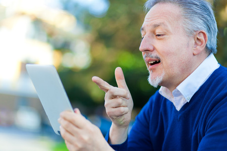 Mature man using a tablet at the parkの写真素材