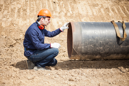 Man examining a pipe in a construction site