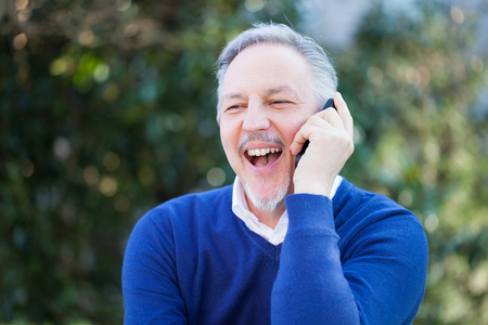 Senior handsome man talking on the phone in a park