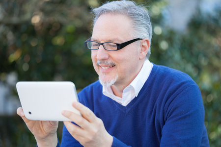 Senior smiling man using a digital tablet