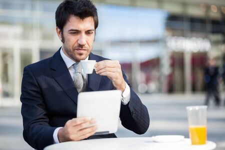 Businessman reading his digital tablet during breakfastの写真素材