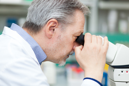 Researcher looking through microscopeの写真素材