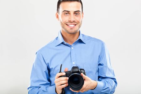 Smiling photographer using his camera isolated on whiteの写真素材