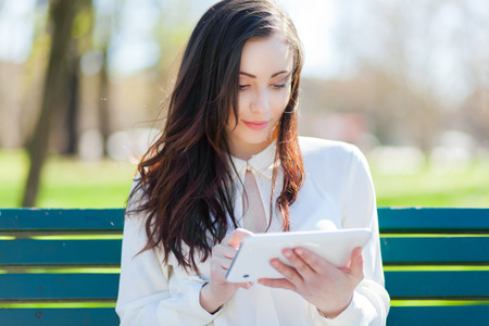 Young woman with tablet on the benchの写真素材