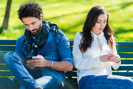 Couple not talking to each other typing on mobile phones Couple not talking to each other typing on mobile phones