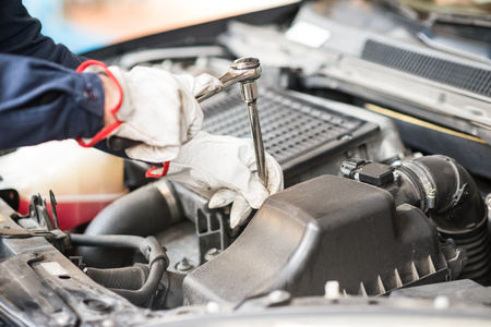Detail of an auto mechanic at work on a car in his garage