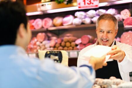 Shopkeeper serving a customer in a grocery storeの写真素材