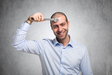 Smiling man using a wrench to adjust his mindの写真素材