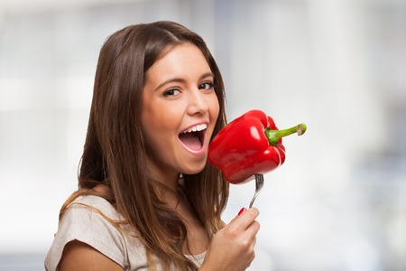 Funny diet concept, woman trying to eat a pepper on a forkの写真素材