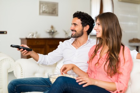 Happy smiling couple watching tv. Shallow depth of field, focus on the man