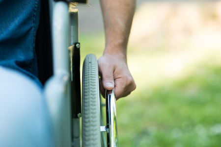 Close-up of male hand on the wheel of a wheelchairの写真素材