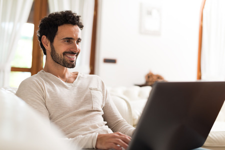 Portrait of a smiling young woman using a tablet computer in her apartmentの写真素材