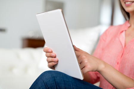 Portrait of a smiling young woman using a tablet computer in her apartment