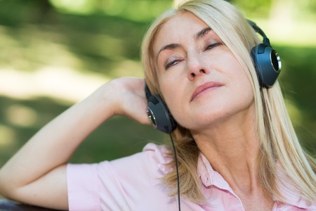 Portrait of a mature woman listening music outdoorsの写真素材