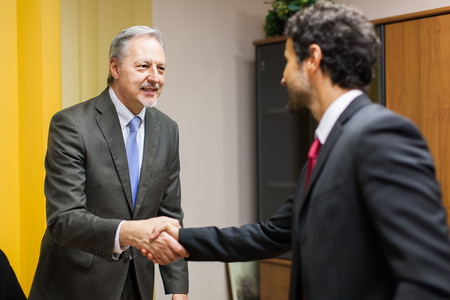 Businessman welcoming a guest in his officeの写真素材
