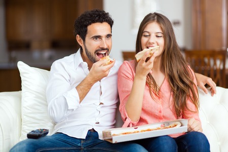 Couple with pizza and TV remoteの写真素材